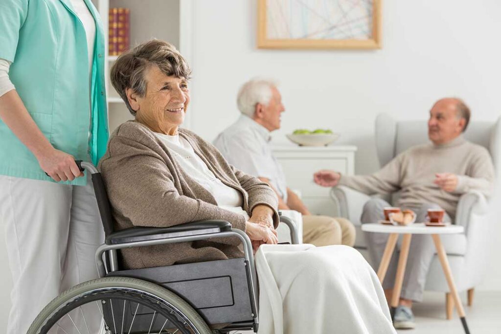 A group of seniors sitting together and talking in a comfortable common room.